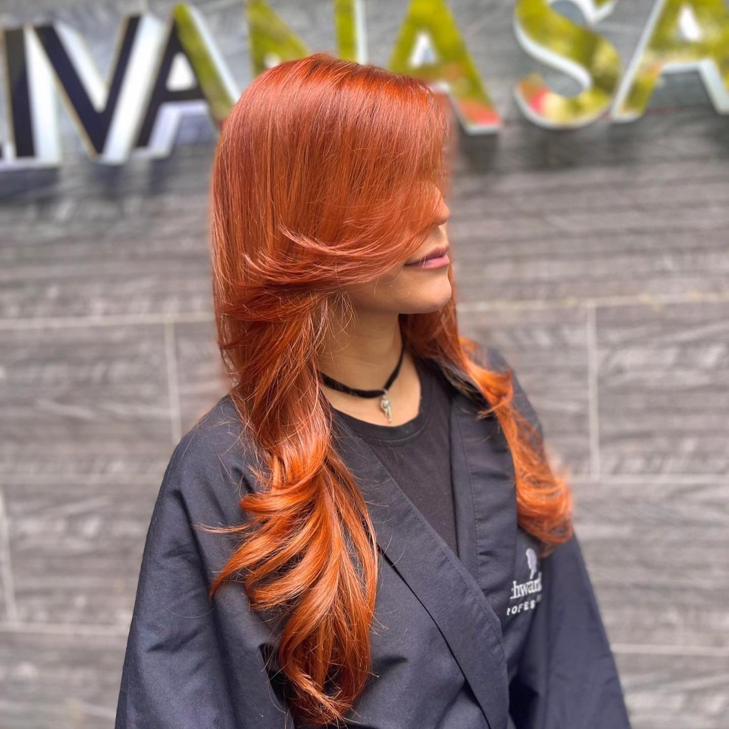 Clienta con cabello cobrizo en capas frente al letrero de Livana Salón